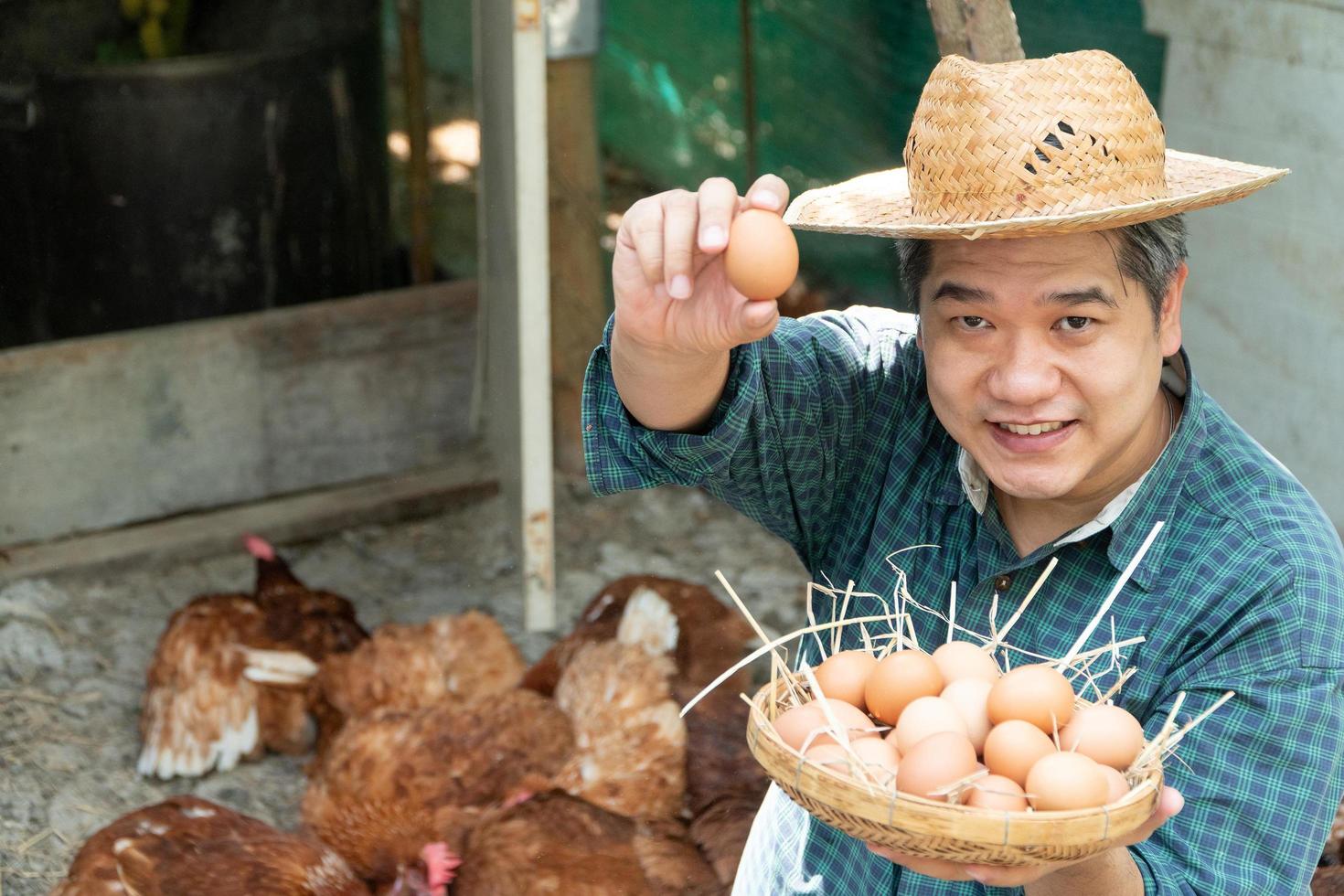 los granjeros asiáticos sostienen una canasta de huevos con la mano izquierda y la mano derecha sosteniendo el huevo y sosteniendo. en una granja de pollos en su propia área de origen foto