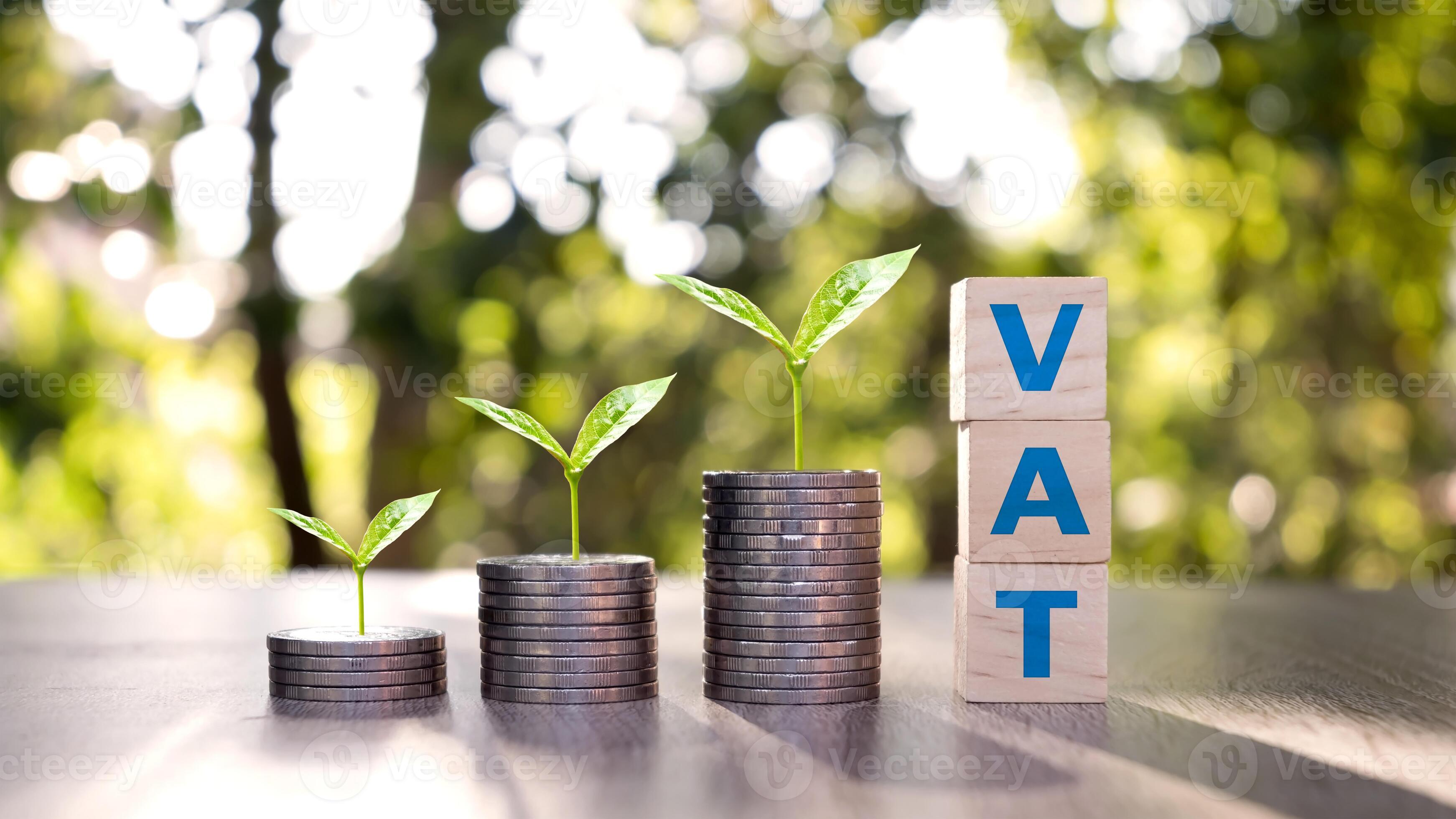 wooden block with vat text and tree on stacked coins vat concept VAT charged by the government