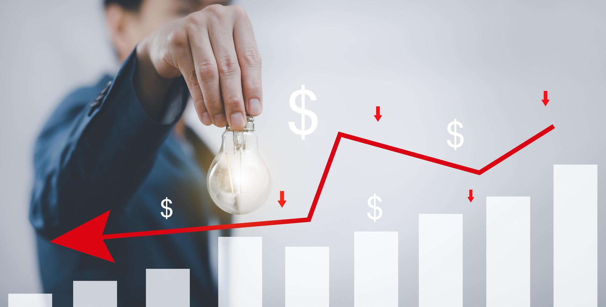 el hombre de negocios que sostiene una bombilla con pérdidas en el concepto del gráfico del mercado de valores, el gráfico del mercado y las flechas rojas caen al suelo, lo que indica la recesión económica que ocurrirá en 2021 foto