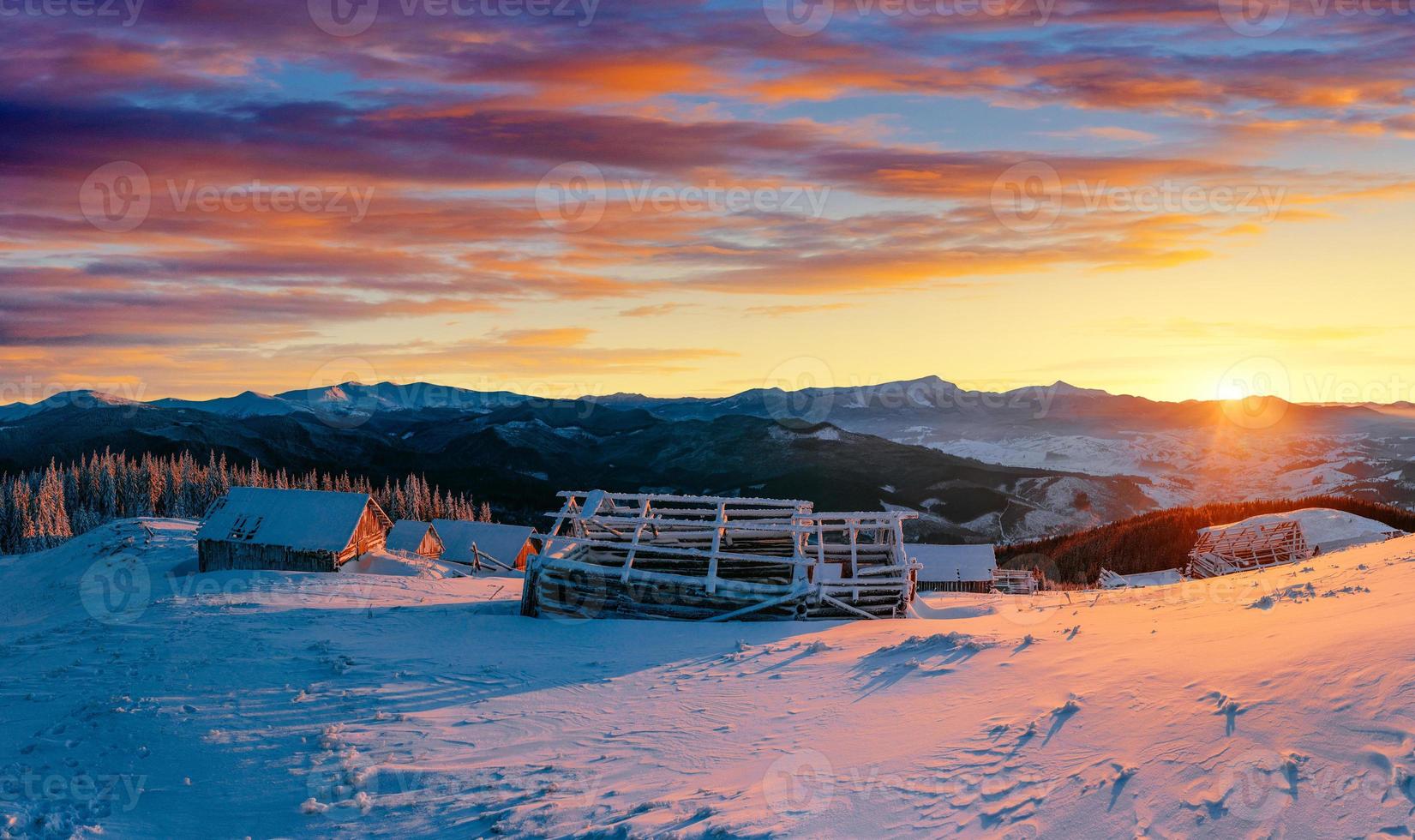 Fantastic sunset over snow-capped mountains and wooden chalets. photo