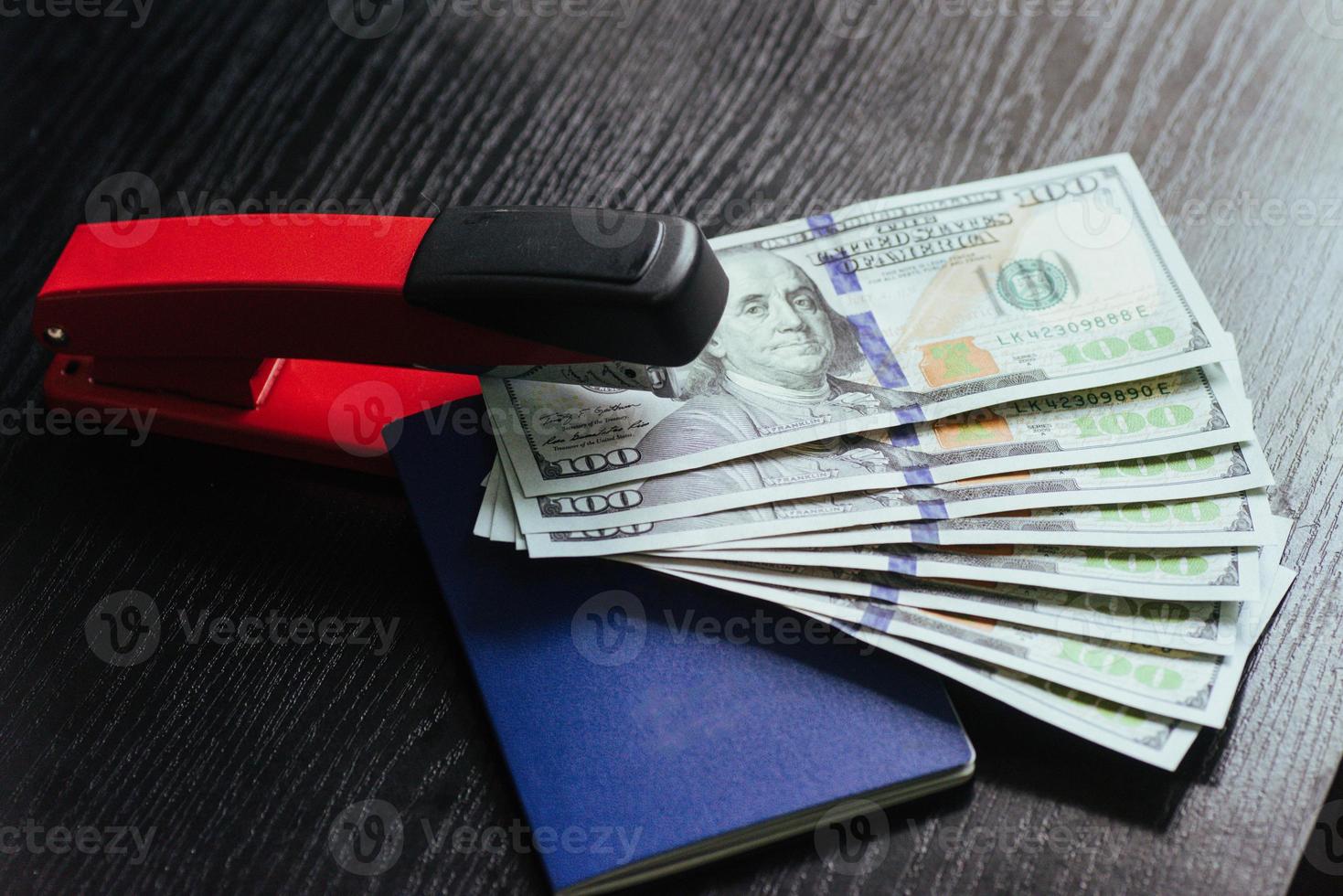 Top view of passport with dollar bills and stapler on wooden table photo