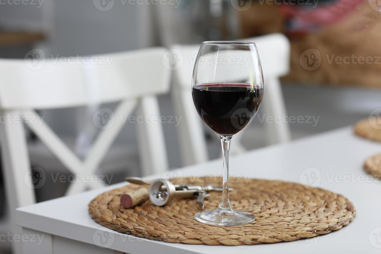 una copa de vino y algunas herramientas de vino sobre una superficie de madera blanca. vino tinto foto