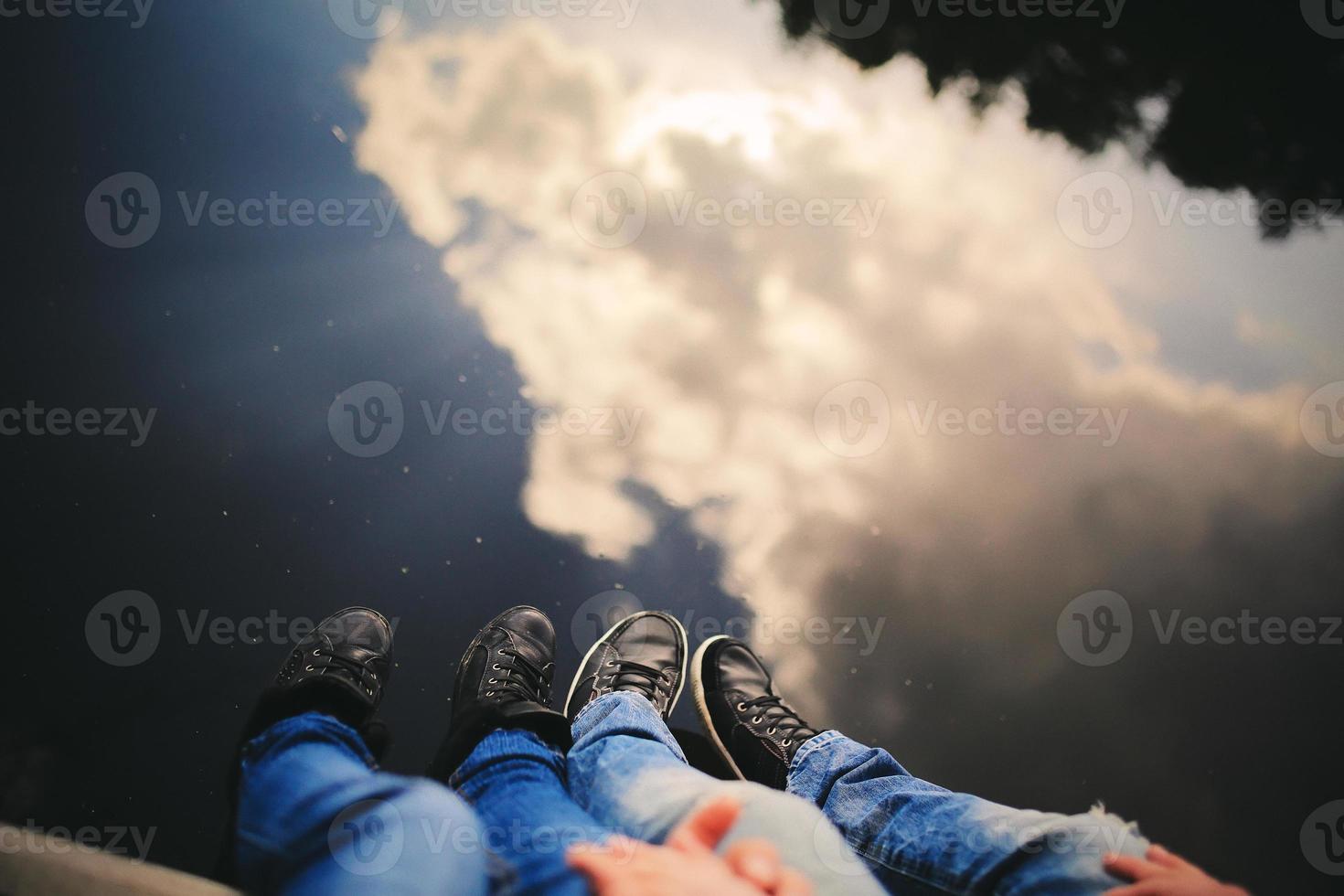 pareja amorosa sentada cerca del río en el puente tomados de la mano. foto