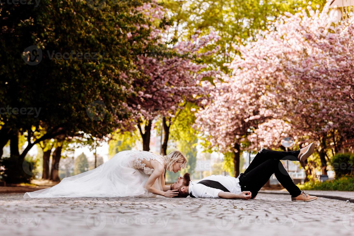 stylish couple lying on the ground in old town in spring. couple having fun together on urban background. couple enjoying spring. photo