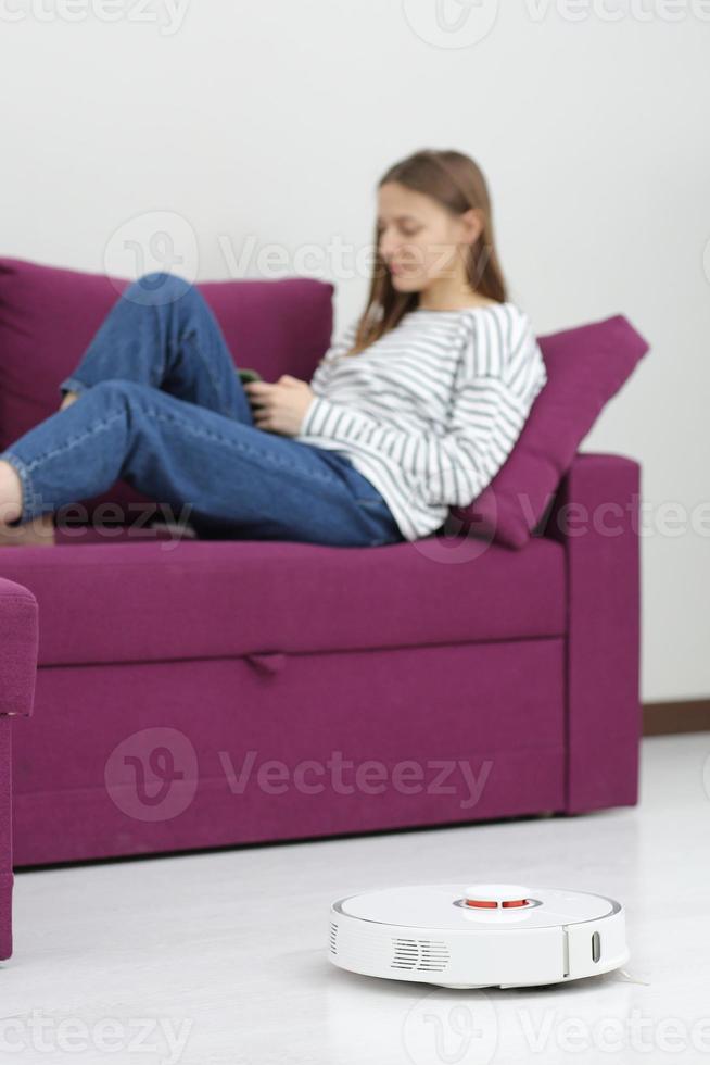 robot cleaner cleans. girl resting at home on the couch, while the robot vacuum cleaner. concept time for yourself. smart House. modern girl optimizes her time. robots concept. selective focus photo