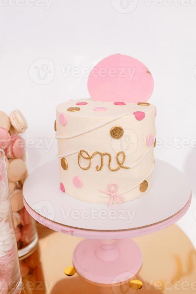 Beautiful birthday cake with pink decor for the birthday of a yearling child. Candy bar with macaroons and marshmallows photo