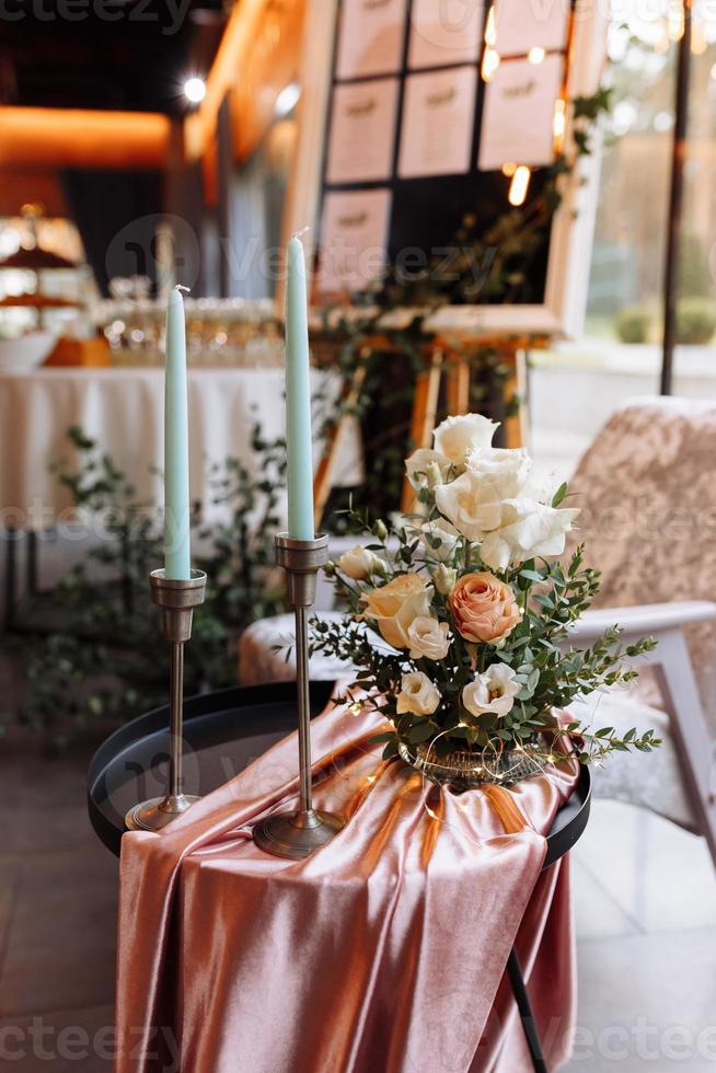 festive Decor. Details. white long candles on gold candlesticks. flower composition with white, yellow, pink flowers and greenery on the black metal table and pink tablecloth. Wedding decorations photo