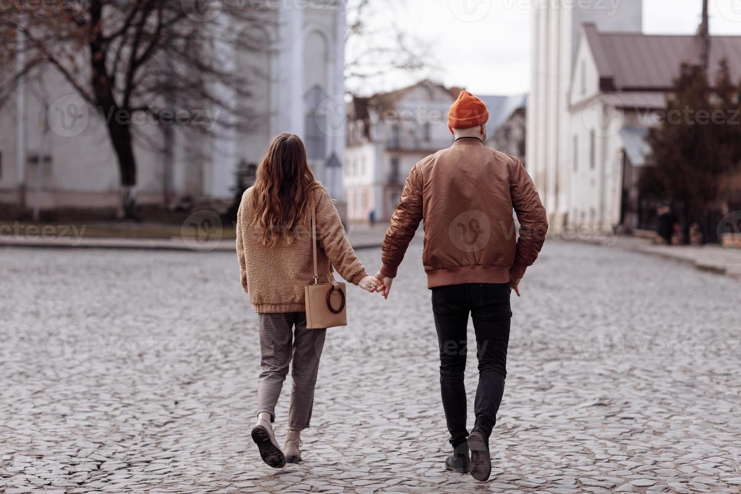 Love story of the beautiful young man and woman walking on the open air the city. embrace on a city walk. copy space. loving couple walking in the city in the open air photo