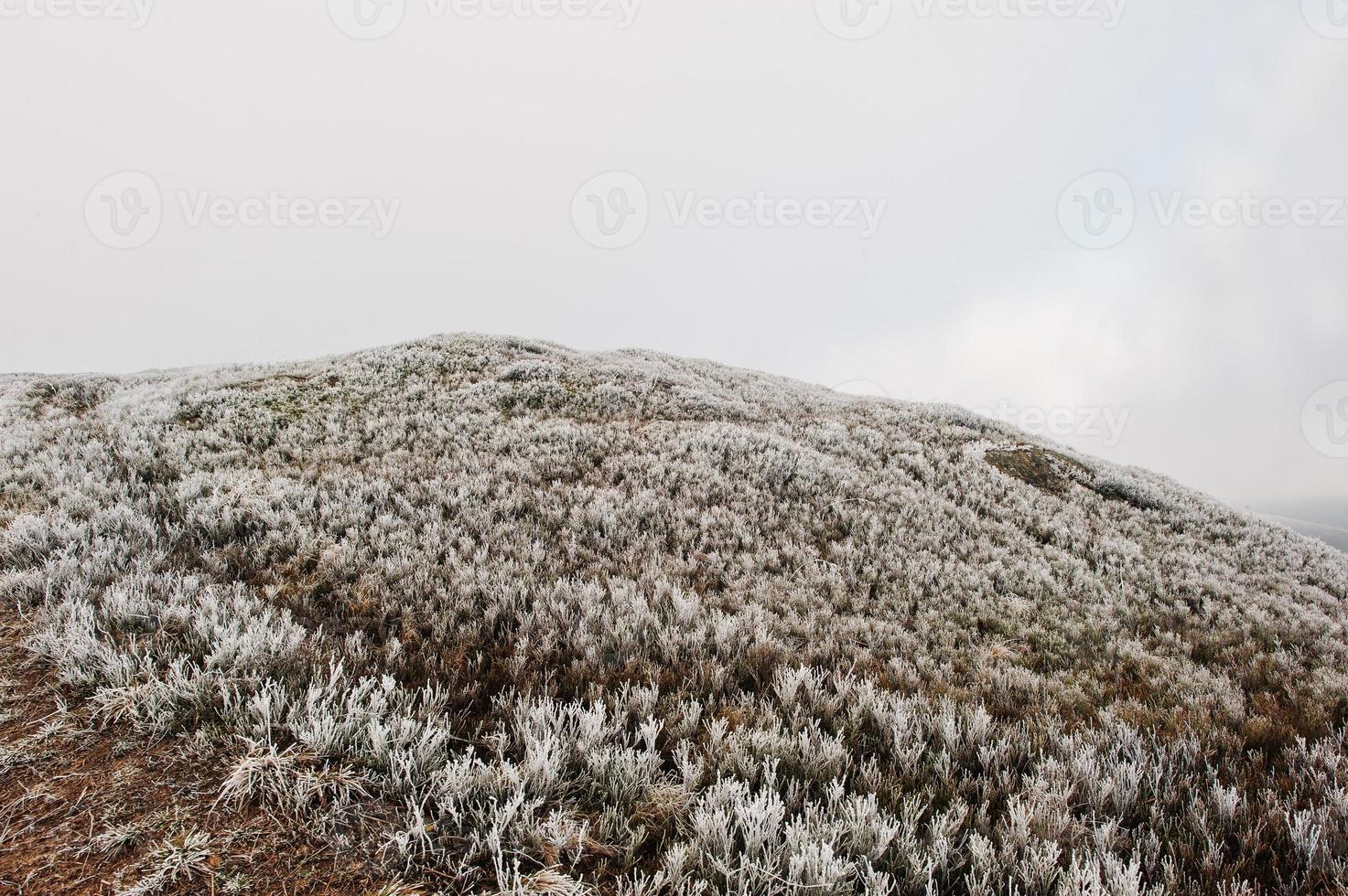 Mountain hill with frost grass and sunlight from clouds photo