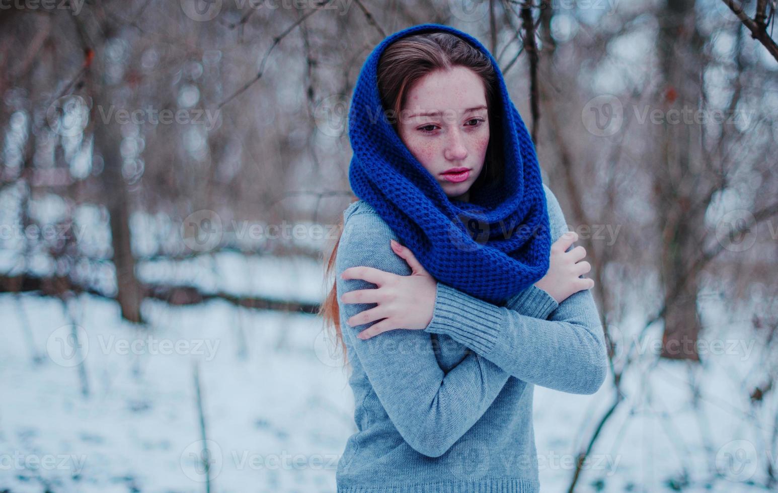 Portrait of young red hair girl with freckles wearing at blue knitted wool scarf in winter day. photo