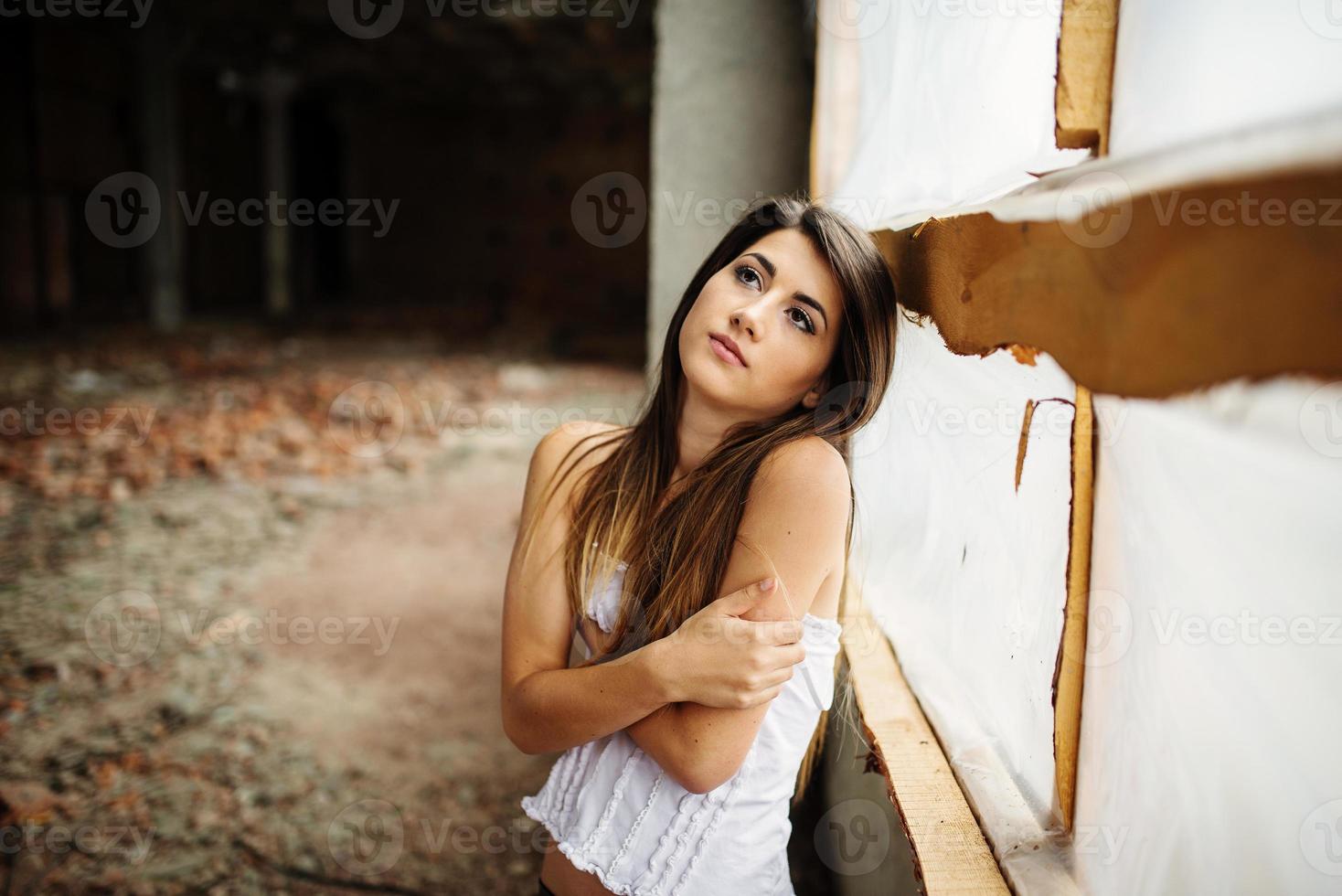 Close up portrait of young cute brunette girl posed on abandoned place. photo