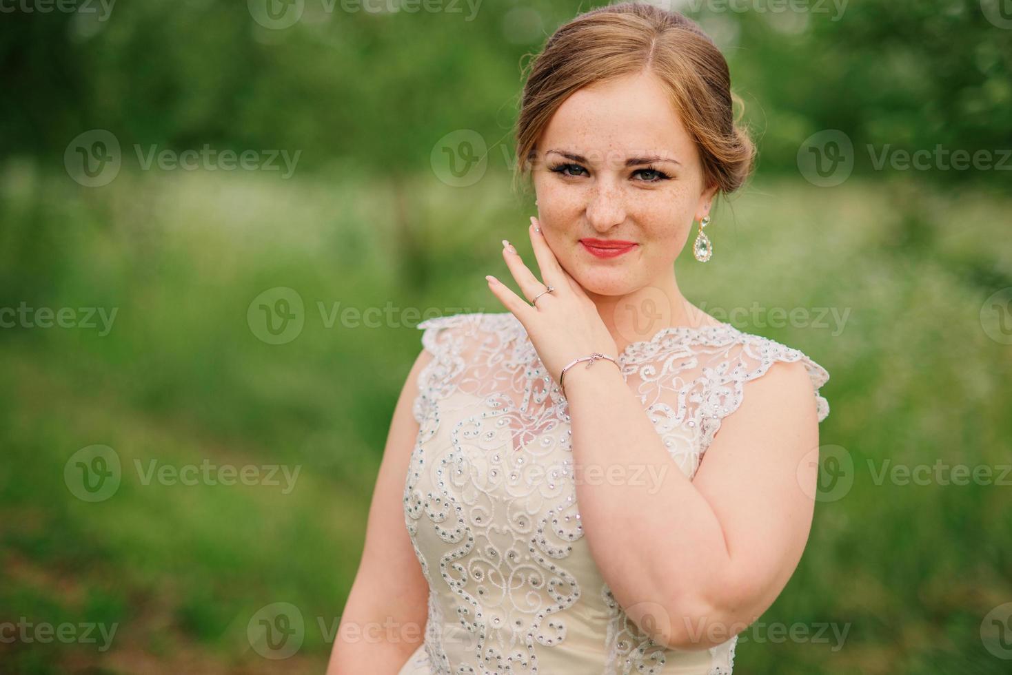 joven con sobrepeso en vestido beige plantea jardín de primavera de fondo. foto