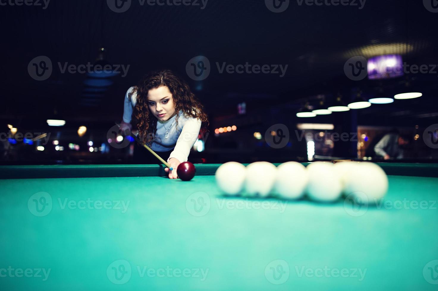 Young curly girl posed near billiard table. Sexy model at black mini mini skirt play russian snooker. Play game and fun concept. photo