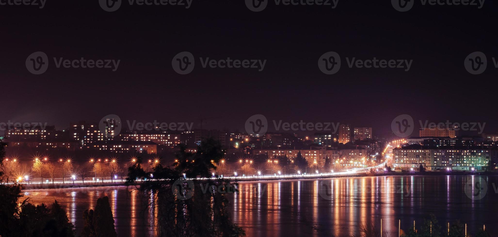 panorama de las luces de la ciudad nocturna y reflejos en el lago en ternopil, ucrania, europa. foto