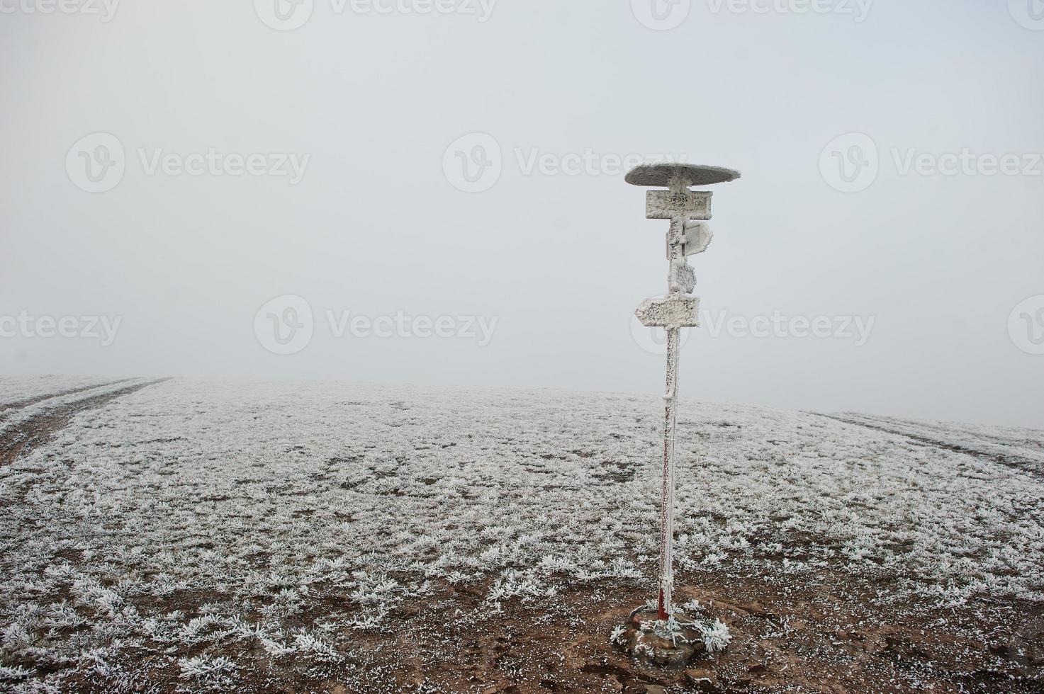 Frozen pointer with directional arrows at mountains photo