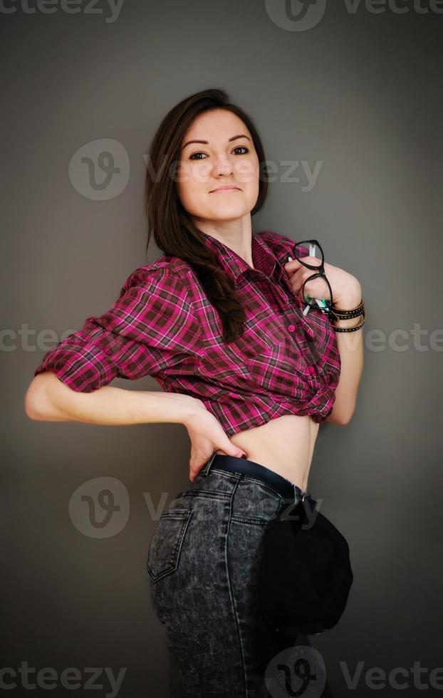 retrato de una chica morena con gorra con ropa informal en la pared gris de fondo. foto