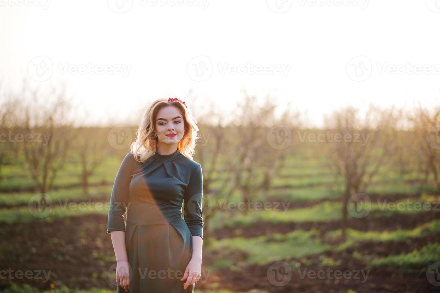yong elegancia chica rubia en vestido verde en el jardín en primavera al atardecer. foto