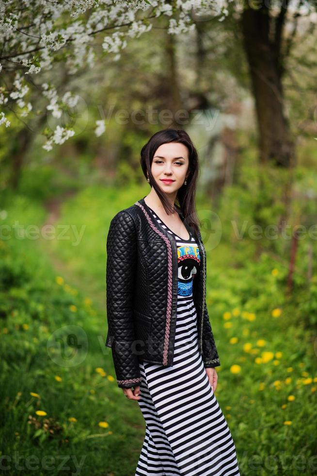 Brunette girl at leather jacket posed on spring garden. photo