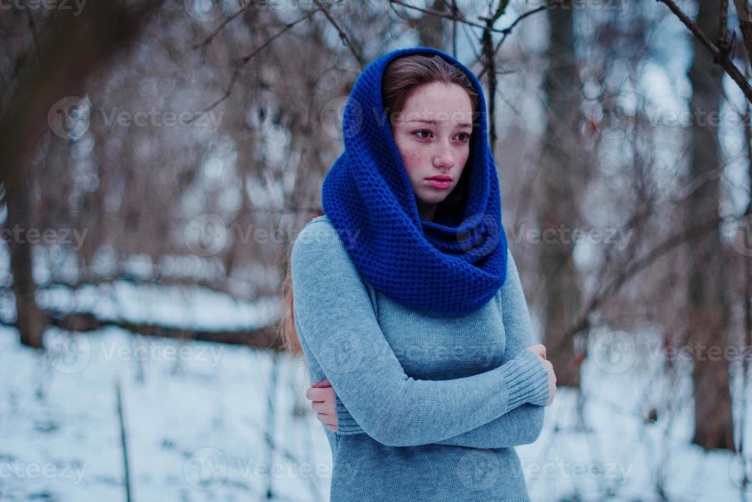 Portrait of young red hair girl with freckles wearing at blue knitted wool scarf in winter day. photo