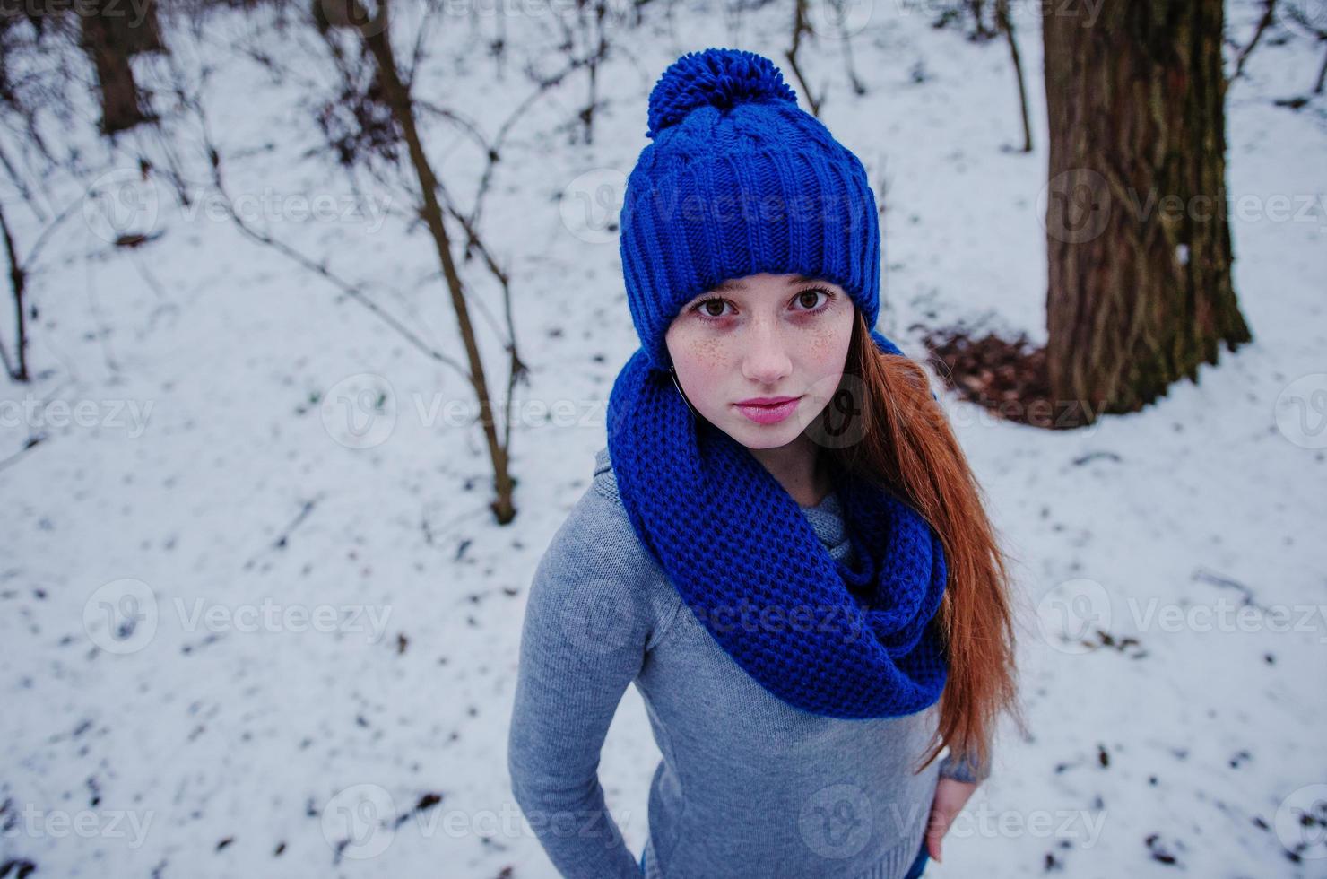 Portrait of young red hair girl with freckles wearing at blue knitted wool hat and scarf in winter day. photo