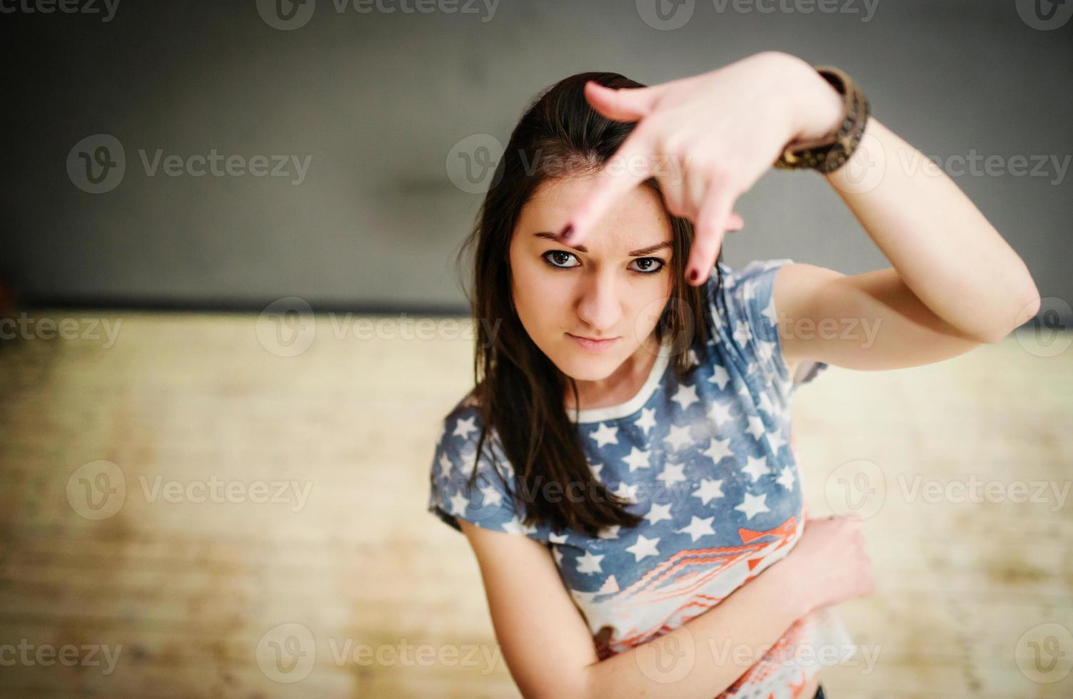 Street dancer girl wearing casual clothes on footless background wooden parquet indoor showing two fingers photo