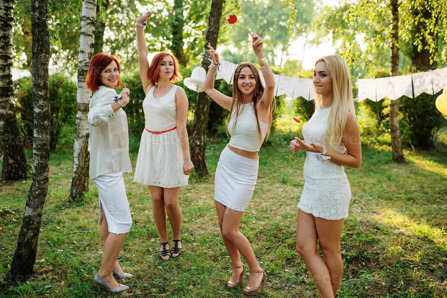 Girls wearing on white dresses having fun on hen party. photo