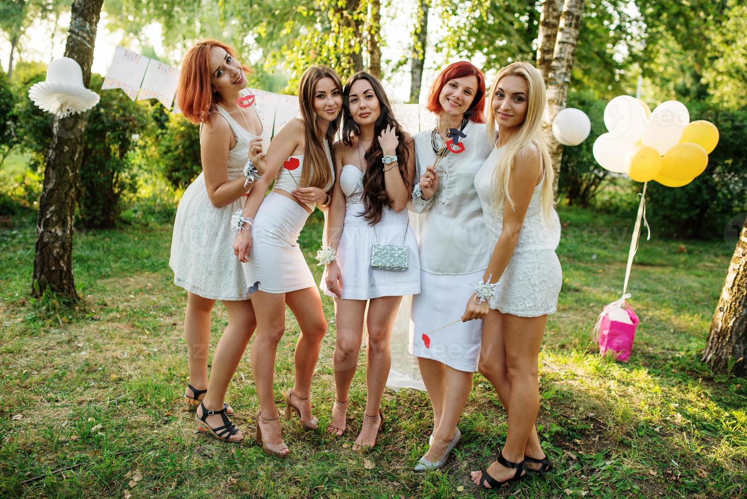 Girls wearing on white dresses having fun on hen party. photo