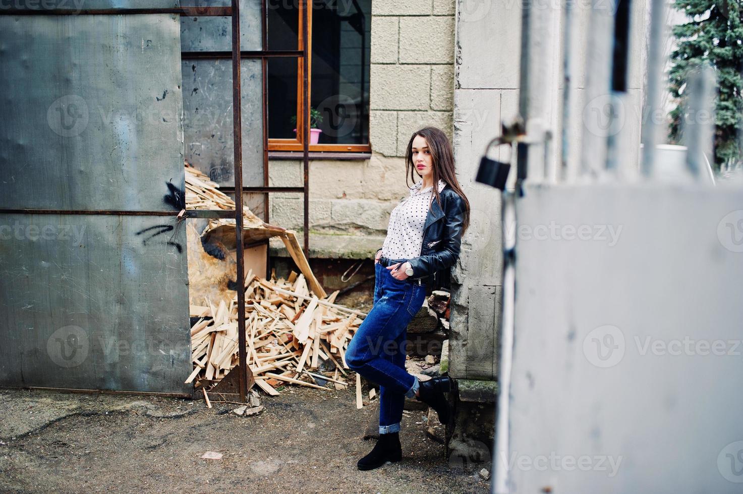 retrato de una joven elegante vestida con una chaqueta de cuero y jeans rotos en las calles de la ciudad. estilo de modelo de moda callejera. foto