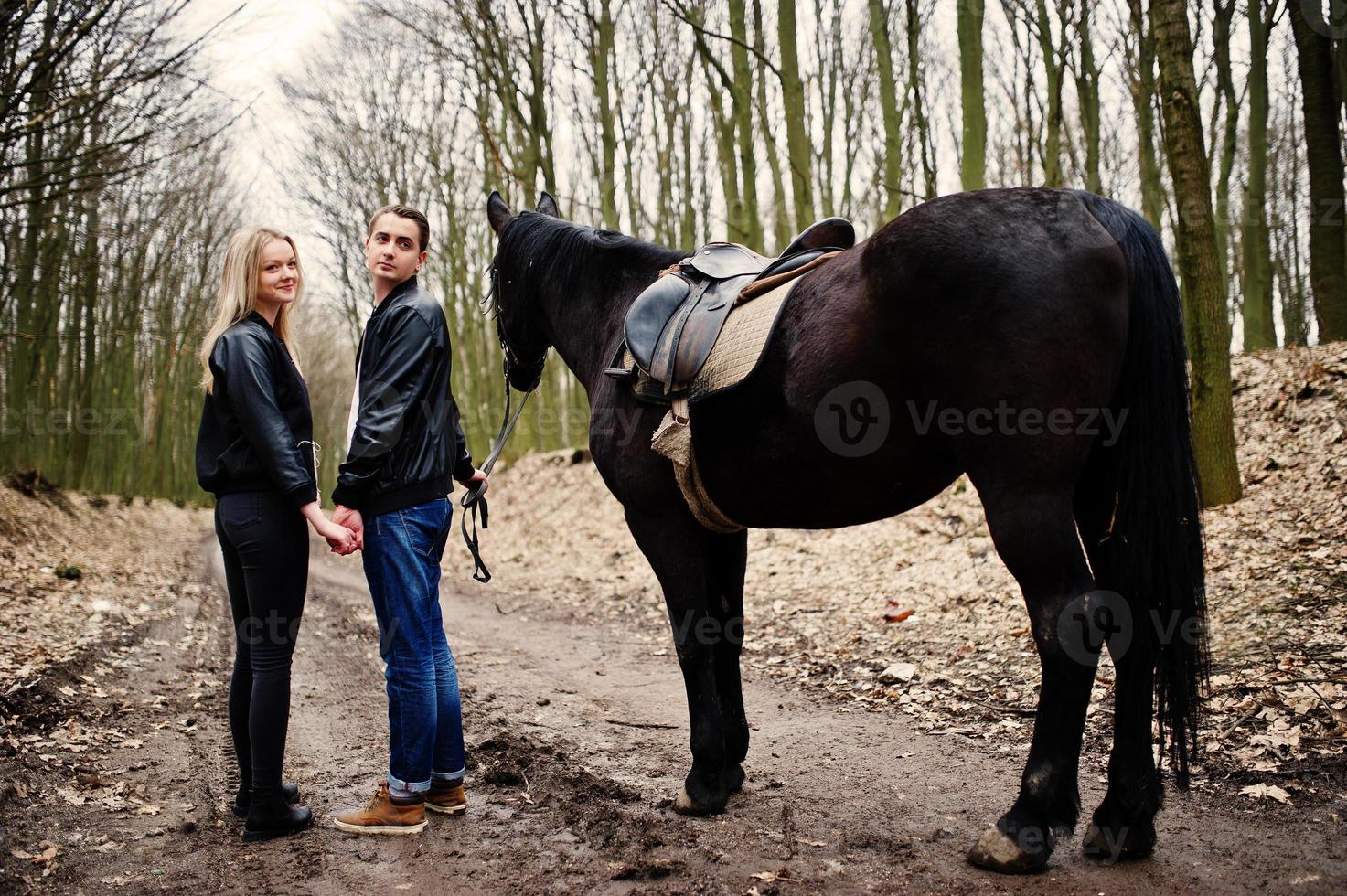 Young stylish couple in love near horse at autumn forest. photo