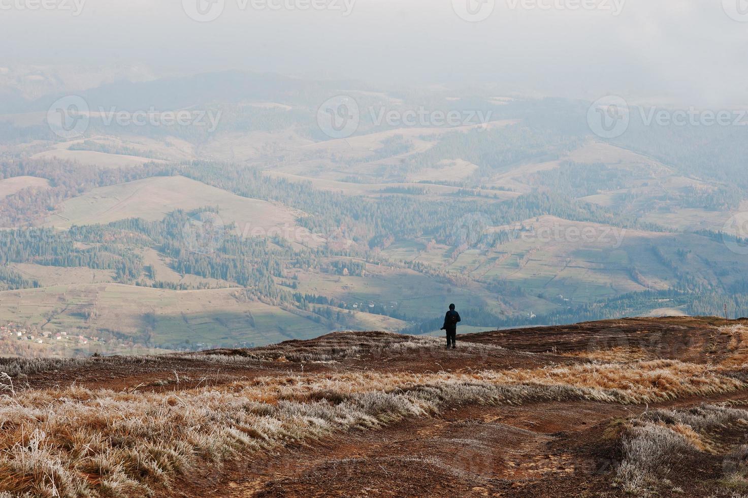 Man stand on hill and looking on moutains. photo