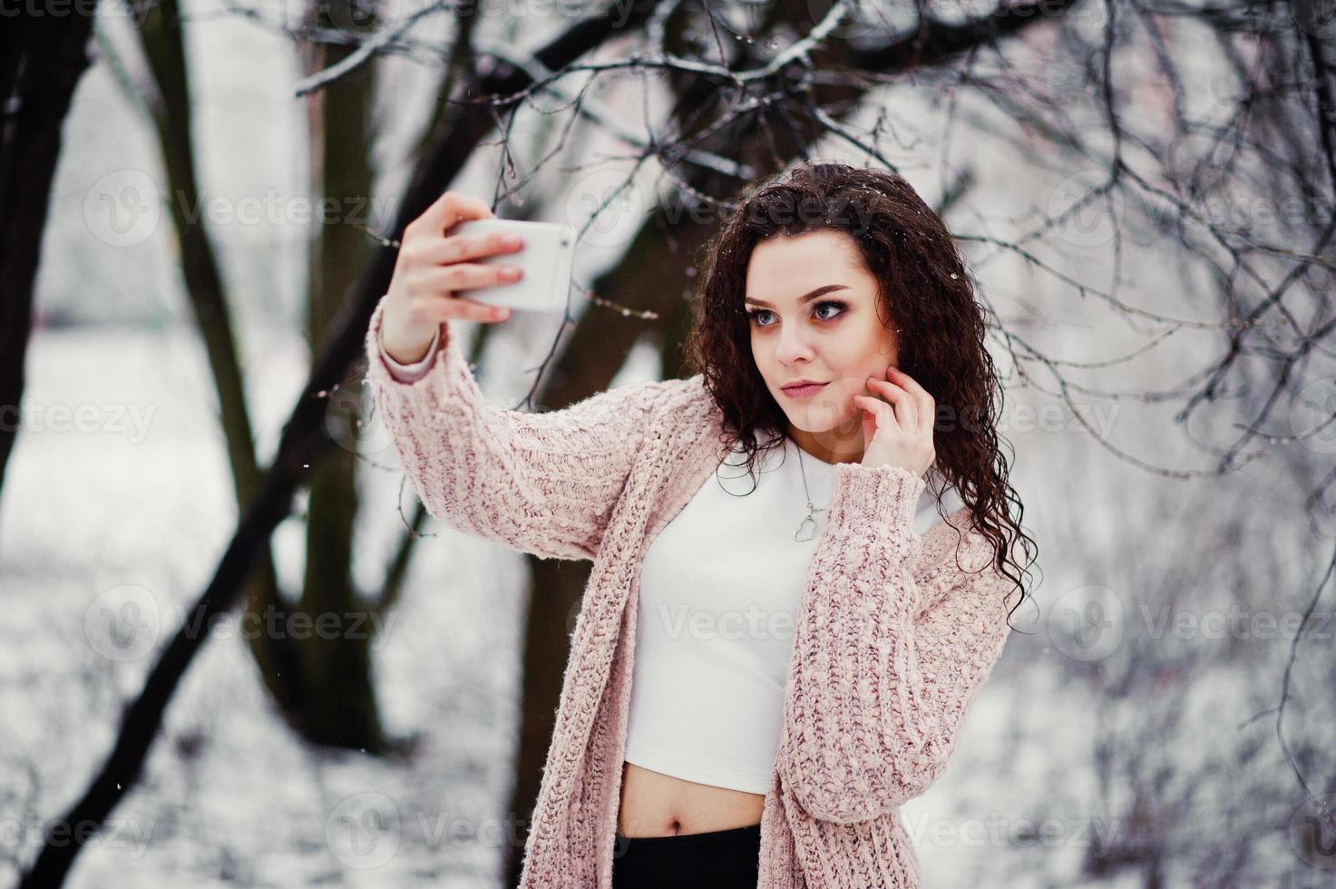 Curly brunette girl with mobile phone photo