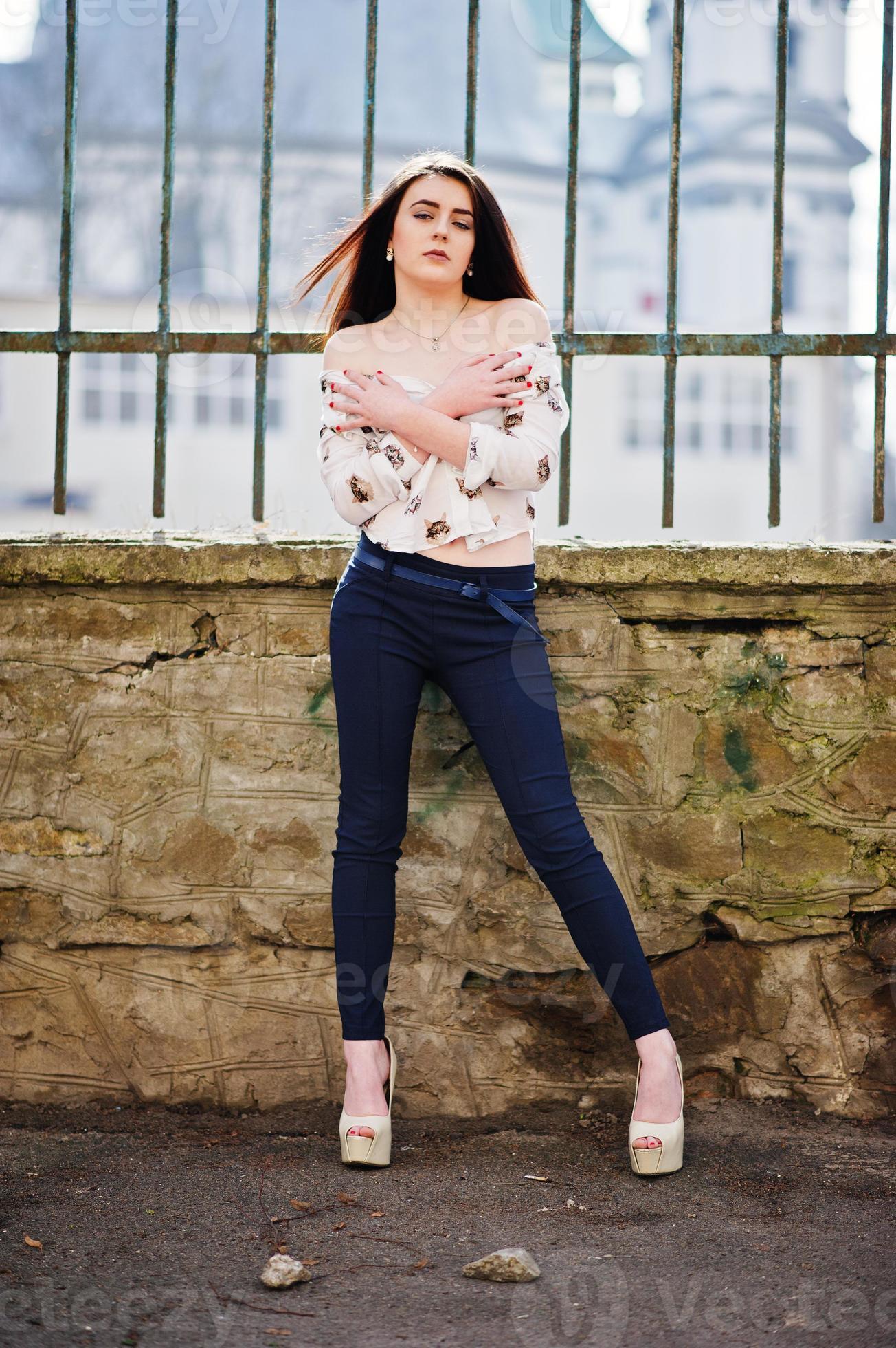 Young stylish brunette girl on shirt, pants and high heels shoes, posed  background iron fence. Street fashion model concept. 6631559 Stock Photo at  Vecteezy