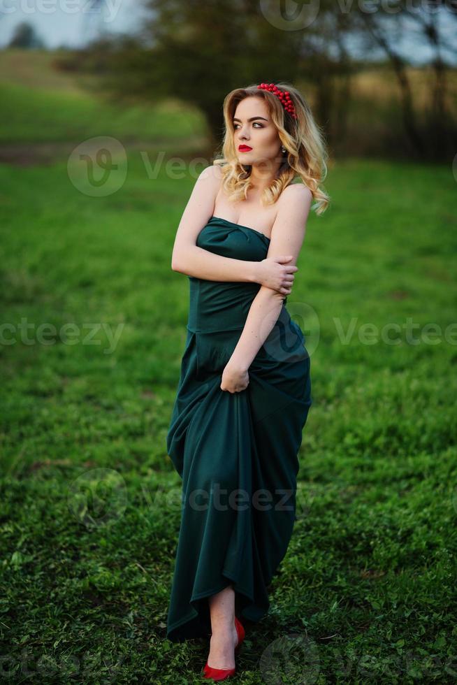 Yong elegance blonde girl at green dress on the garden in spring. photo