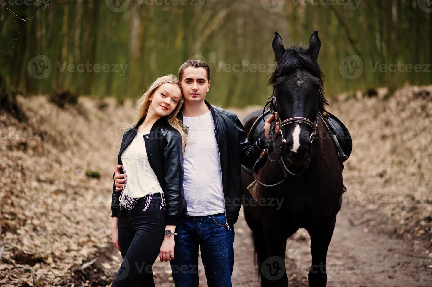 joven pareja elegante enamorada cerca de caballo en el bosque de otoño. foto