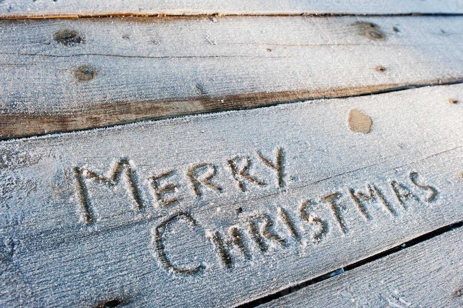 Merry Christmas written on a wooden background with frosts photo