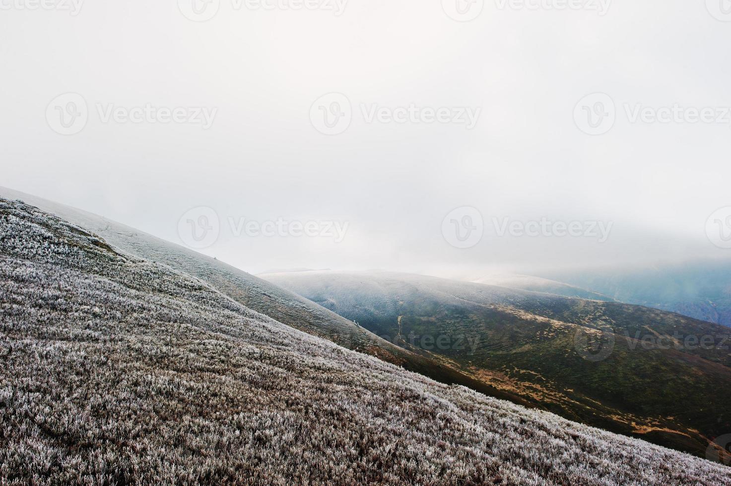 Mountain hill with frost grass and sunlight from clouds photo