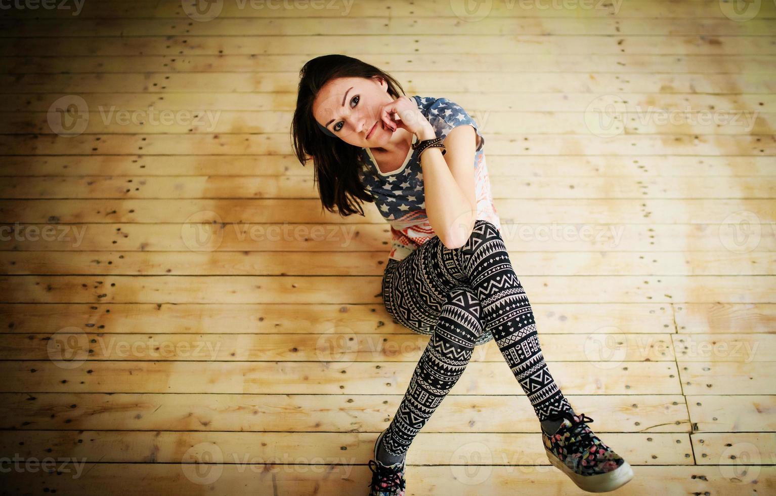 Street dancer girl wearing casual clothes on footless sitting background wooden parquet indoor. photo