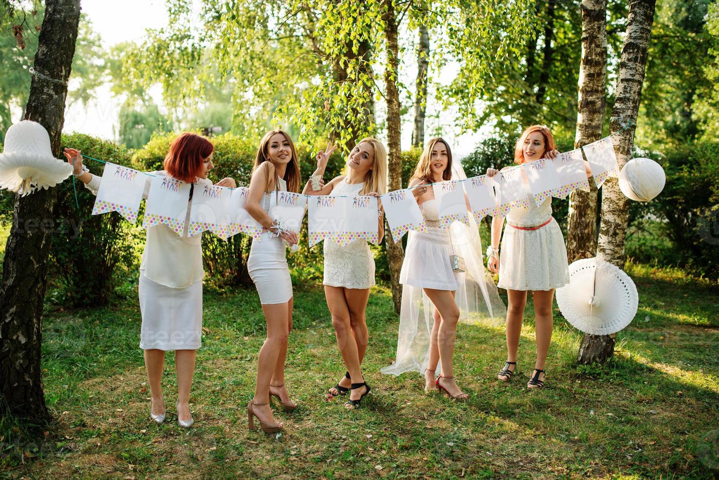 Girls wearing on white dresses having fun on hen party. photo