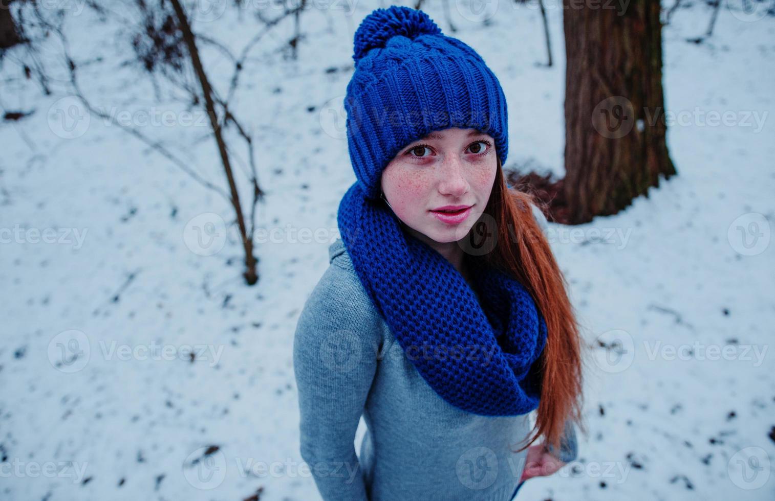 Portrait of young red hair girl with freckles wearing at blue knitted wool hat and scarf in winter day. photo