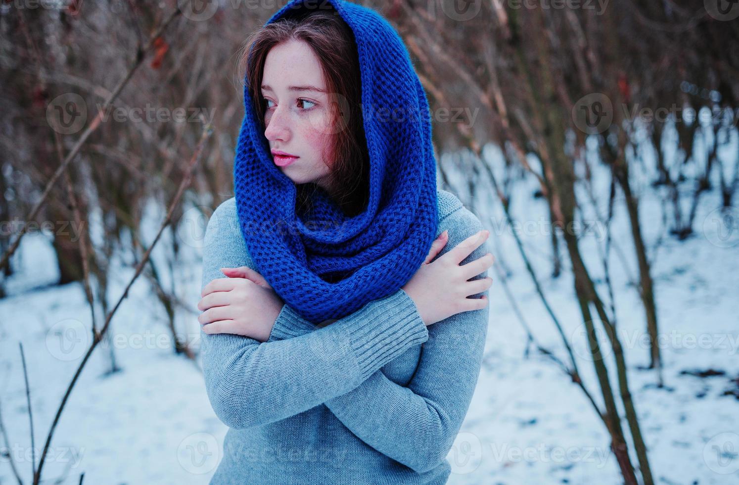 Portrait of young red hair girl with freckles wearing at blue knitted wool scarf in winter day. photo