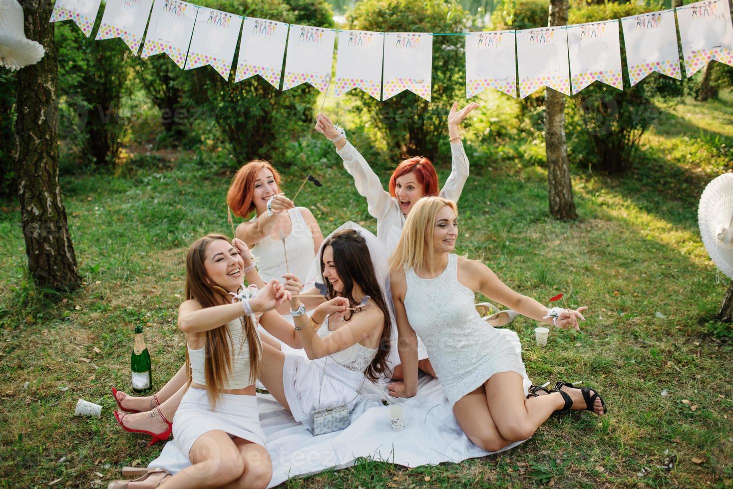 Girls wearing on white dresses having fun on hen party. photo