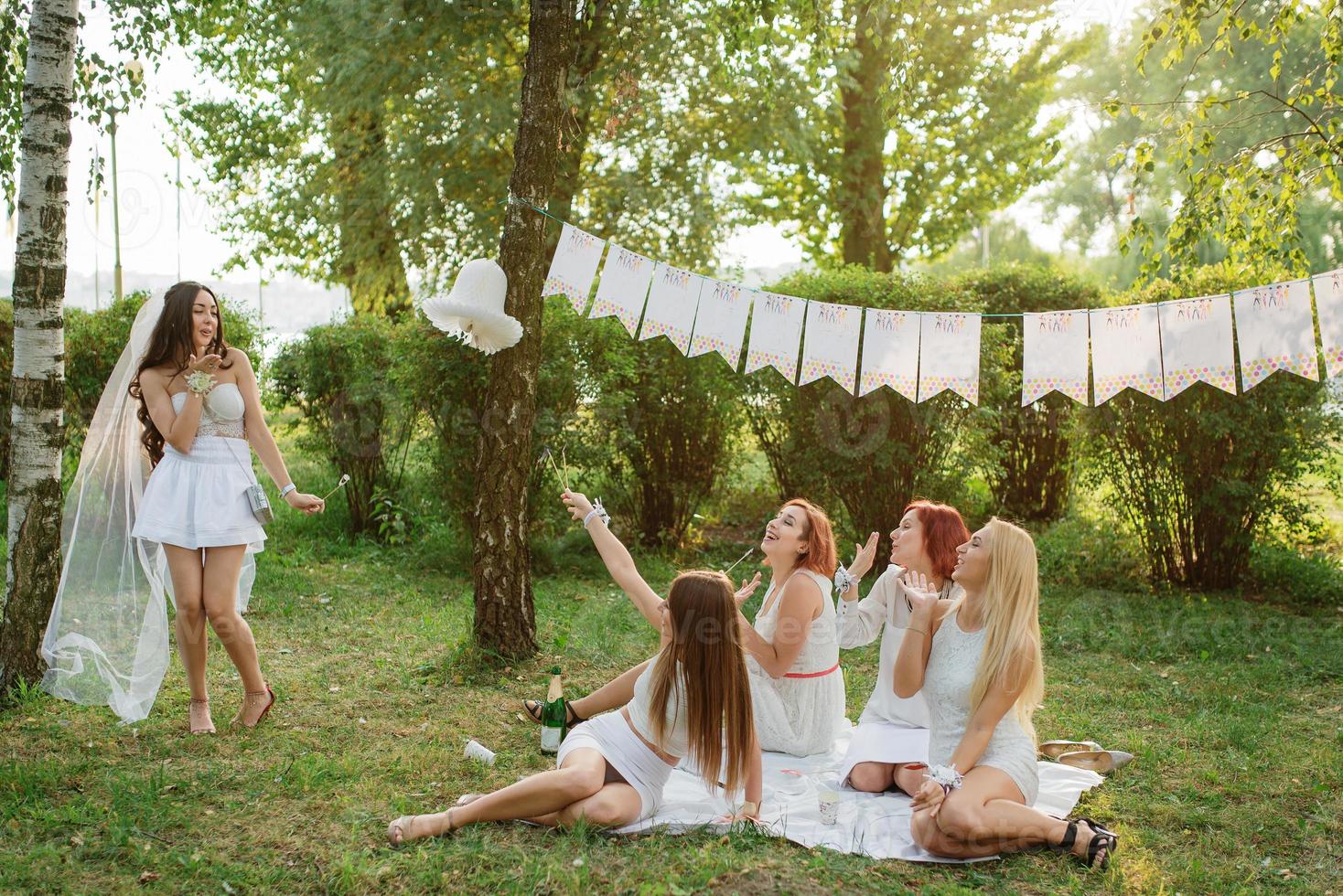 Girls wearing on white dresses having fun on hen party. photo