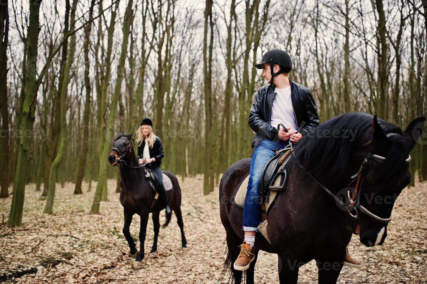 Young stylish couple riding on horses at autumn forest. photo