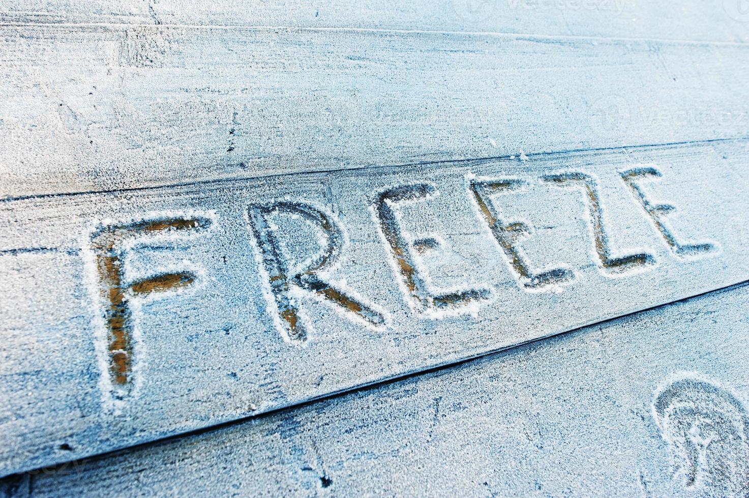 Freeze written on a wooden background with frosts photo