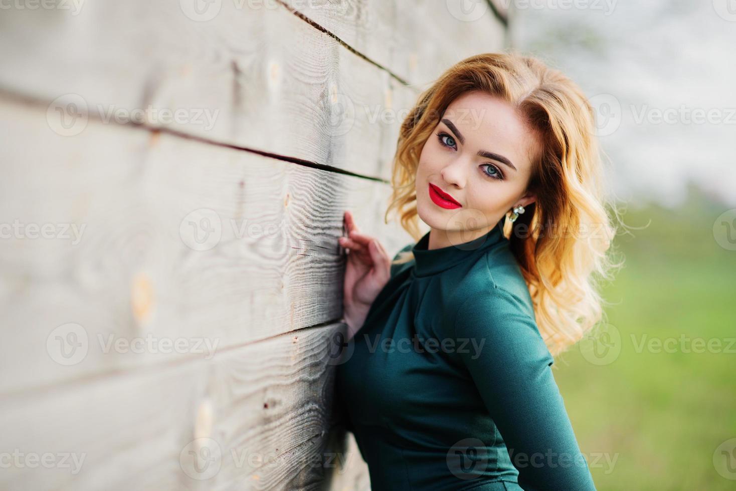 Yong elegance blonde girl at green dress background wooden texture. photo