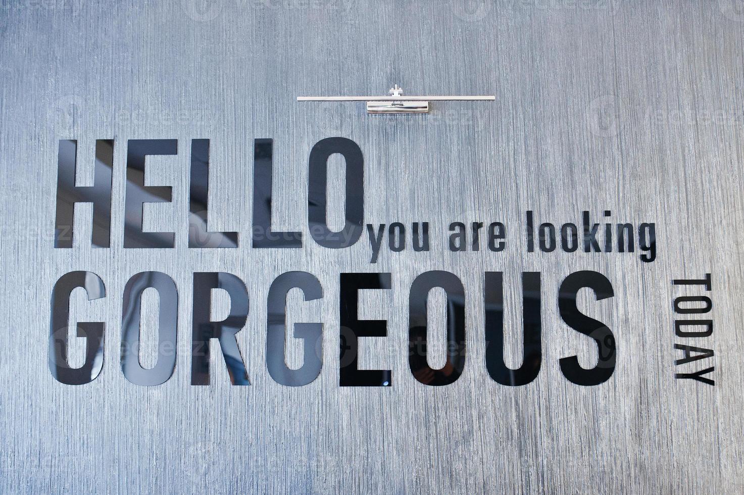 Shiny sign hello you are looking gorgeous, mounted on glossy marble wall. photo