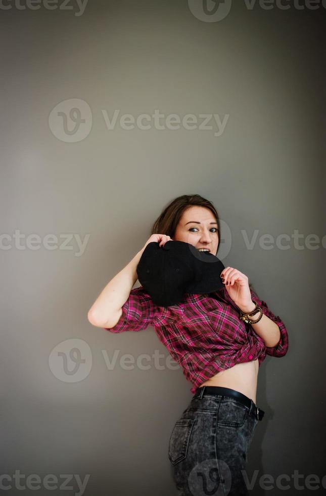 Portrait of brunette girl with cap wearing casual clothes background gray wall. photo