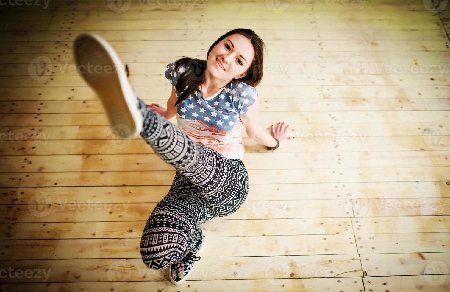 bailarina callejera con ropa informal sobre un fondo de parqué de madera sin pies sentado en el interior. foto