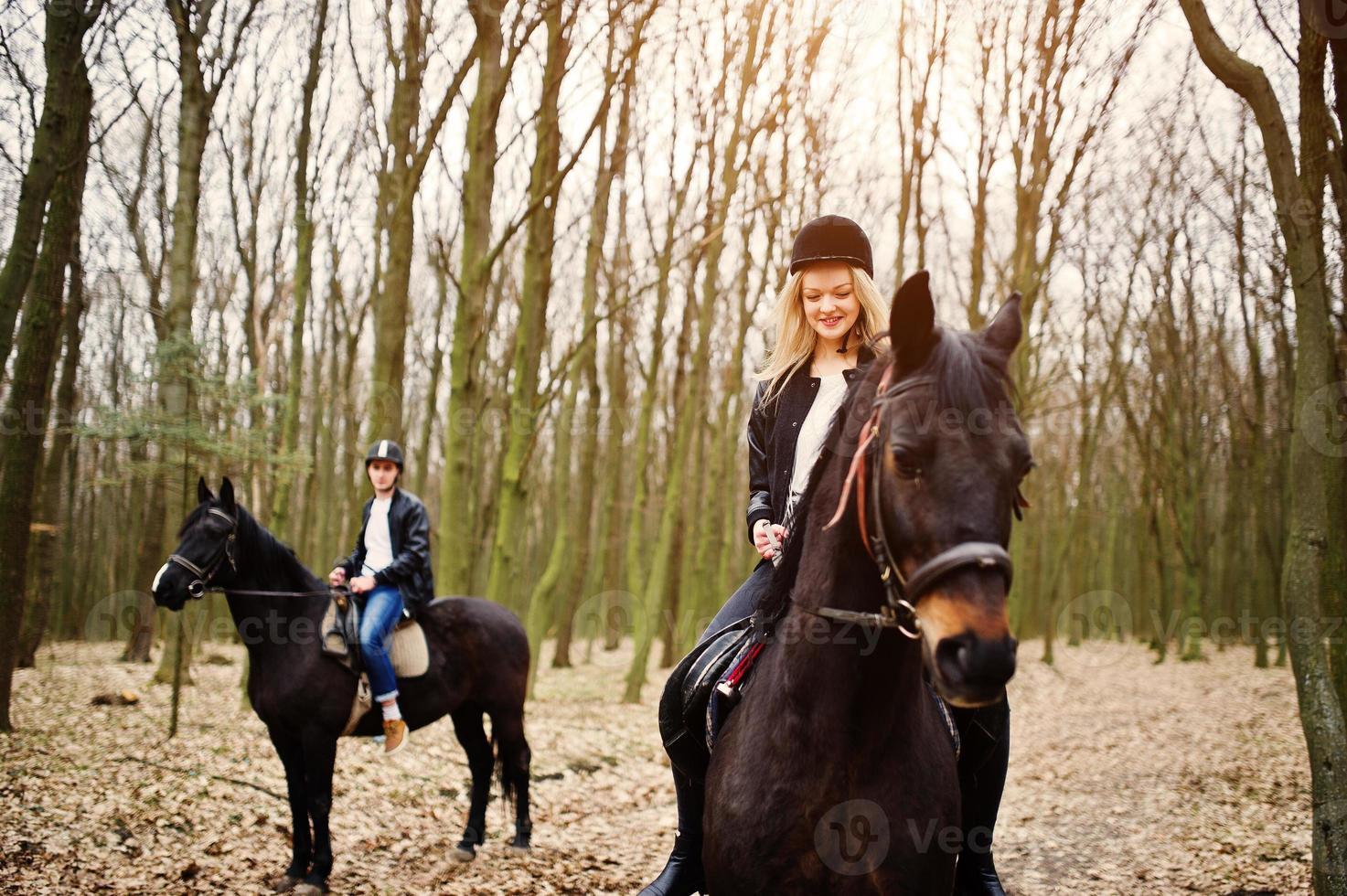 Young stylish couple riding on horses at autumn forest. photo