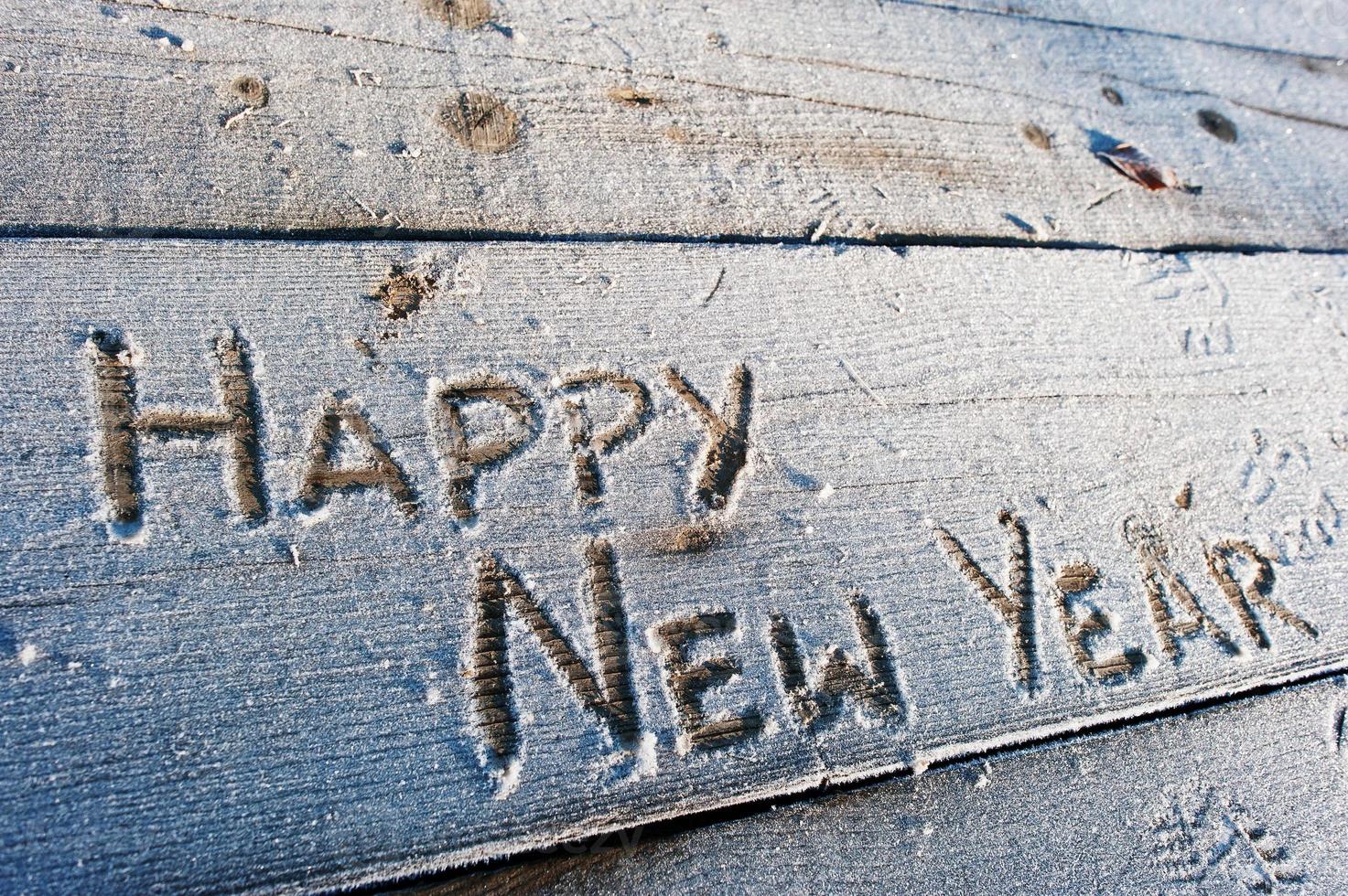 Happy New Year written on a wooden background with frosts photo